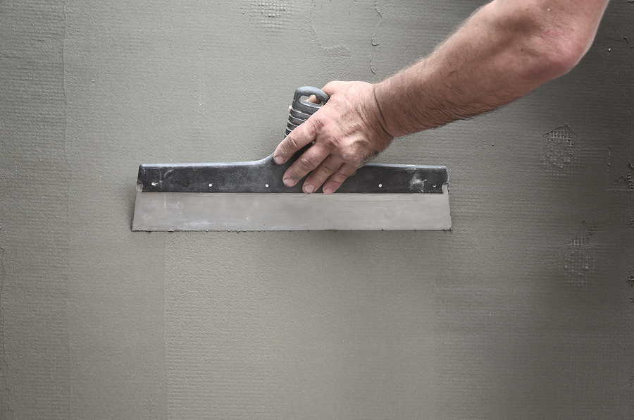 Hands of an old manual worker with wall plastering tools renovating house. Plasterer renovating outdoor walls and corners with spatula and plaster. Wall insulation. Construction finishing works